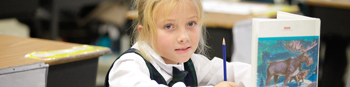 Elementary girl holding a book in class